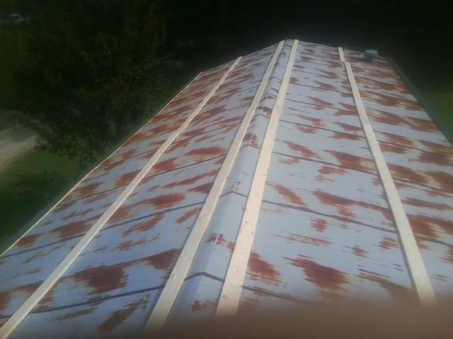 Rusted metal roof panels with new wood purlins before replacement — Storm Damage Roof Repair in Outlook by Roofing Brothers