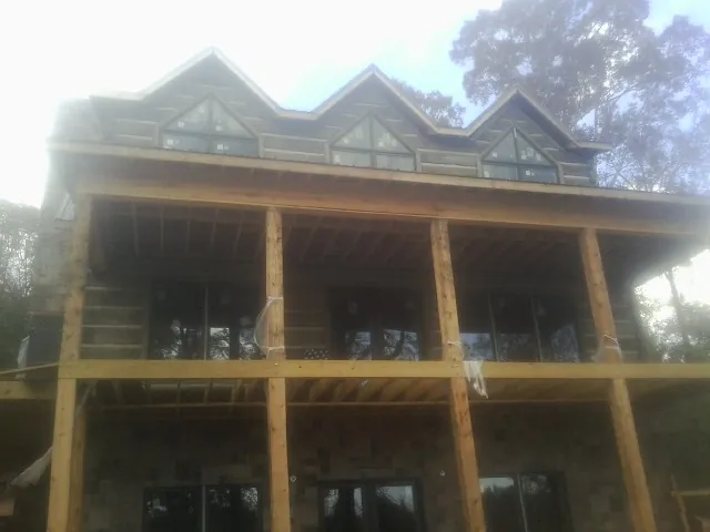 Dormers and porch framing on a large log home under construction — Roof Coating work by our crew in Outlook