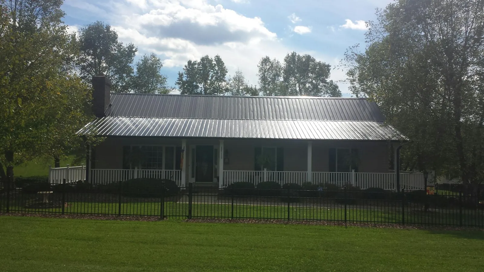 Gray metal roof on a brick ranch with a full width front porch — Gutter Guard Installation work by our crew in Outlook