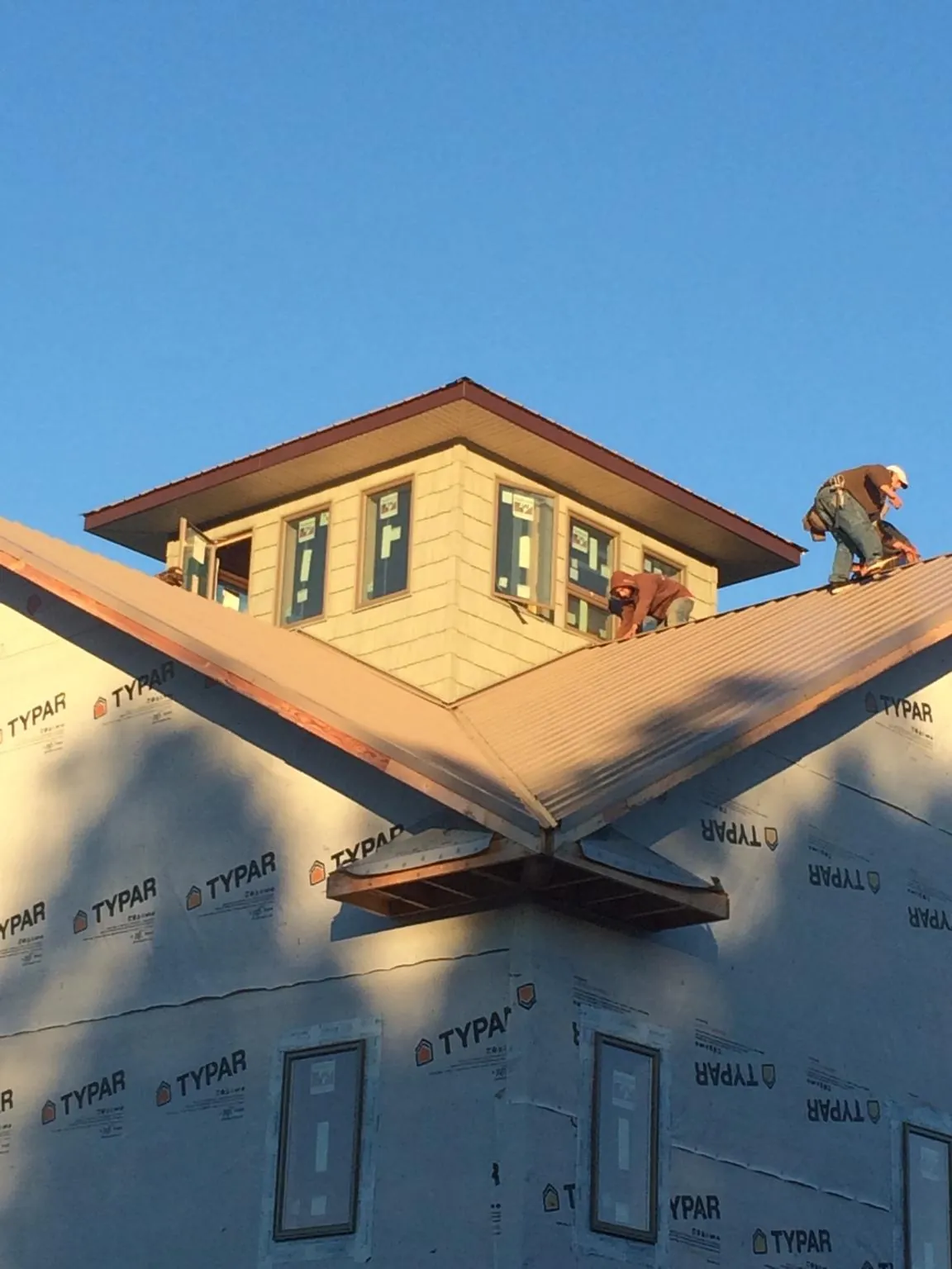 Roofers working around a rooftop cupola on a new metal roof at sunset — Roof Waterproofing in Outlook by Roofing Brothers